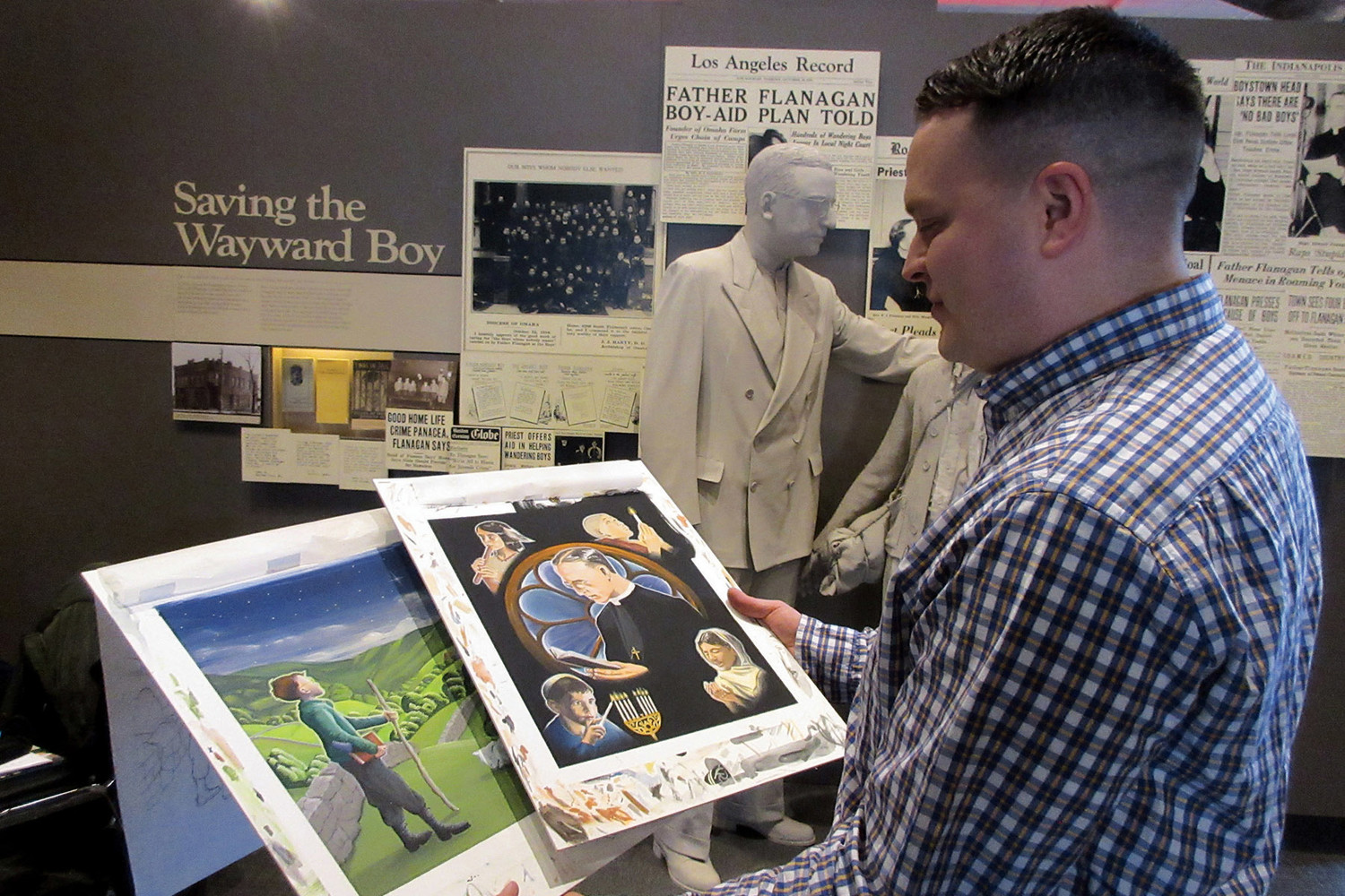 Eli Hernandez looks over examples of his artwork for his children’s book “Dearest Children: A Message Inspired by Father Edward J. Flanagan” March 17 at Boys Town’s Hall of History museum in Omaha, Neb.